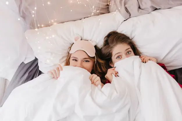 Deux filles serraient une couverture dans leurs bras et se couvraient la bouche